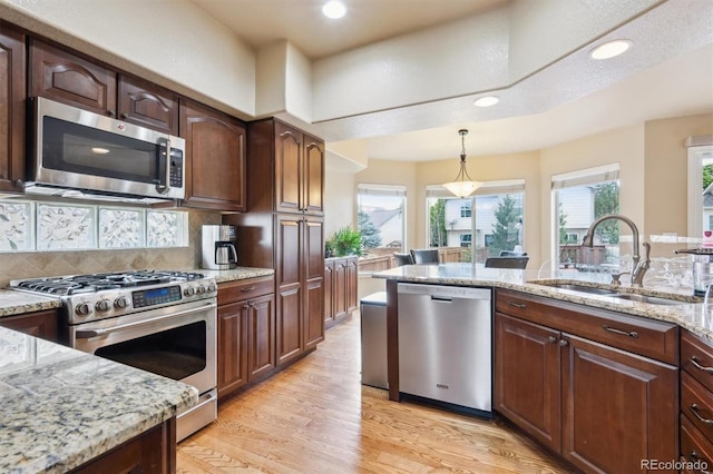 3305 White Oak Ln, Highlands Ranch, CO 80129 - kitchen featuring stainless steel appliances, light wood-style floors, hanging light fixtures, recessed lighting, and light stone counters