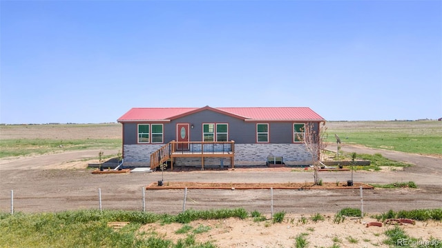 view of front facade with metal roof, fence, and a rural view