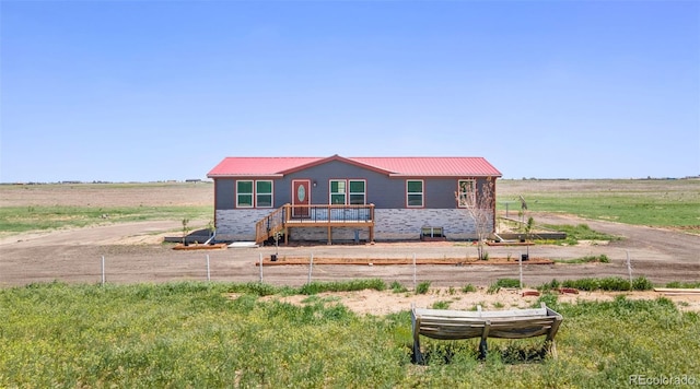 view of front of property with metal roof, fence, and a view of rural / pastoral area