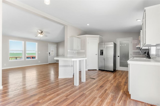 kitchen with stainless steel fridge with ice dispenser, a sink, light countertops, light wood-type flooring, and ceiling fan