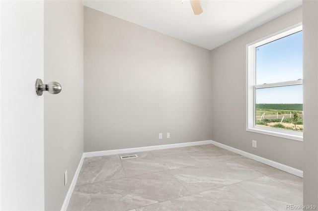 unfurnished room featuring plenty of natural light, baseboards, ceiling fan, and light marble finish floors