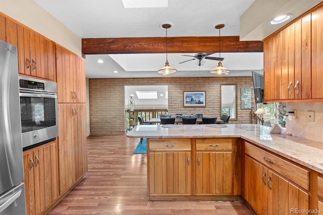 kitchen featuring a skylight, appliances with stainless steel finishes, beam ceiling, and kitchen peninsula