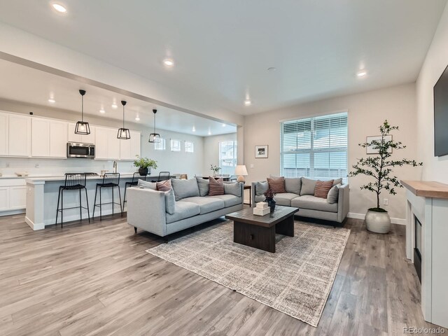 living room featuring light wood finished floors, recessed lighting, and baseboards