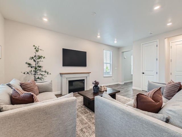 living room featuring recessed lighting, light wood finished floors, baseboards, and a glass covered fireplace