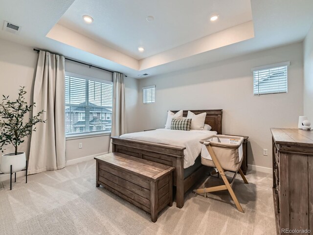 bedroom with light carpet, a tray ceiling, baseboards, and recessed lighting