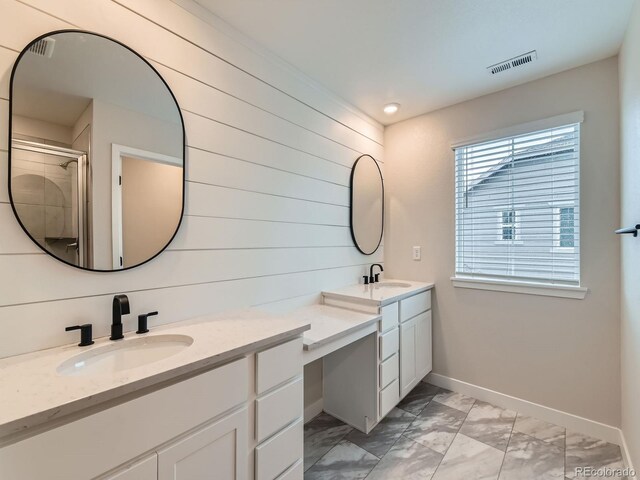 bathroom with marble look tile flooring, double vanity, a stall shower, baseboards, and wooden walls