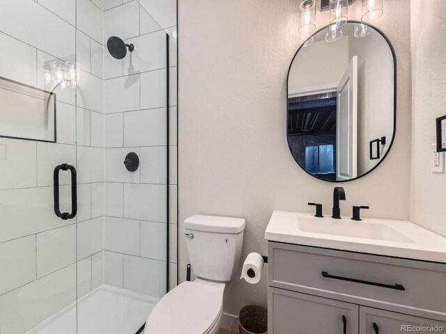 bathroom with a shower stall, toilet, and vanity