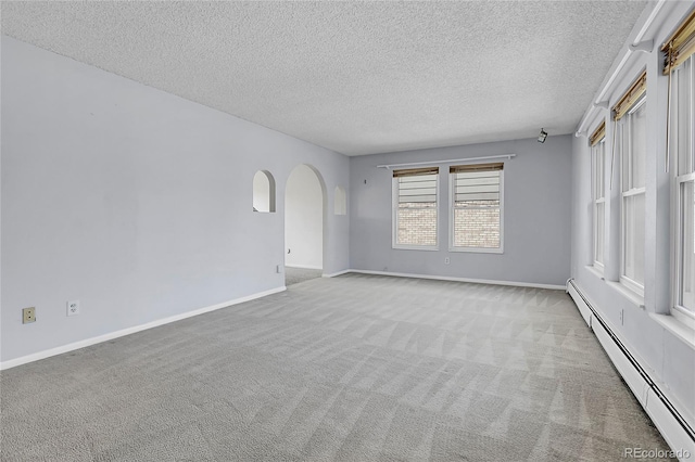 empty room featuring a baseboard radiator, a textured ceiling, carpet floors, arched walkways, and baseboards