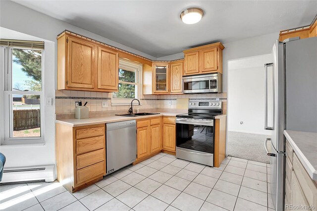 kitchen featuring appliances with stainless steel finishes, a sink, baseboard heating, light countertops, and tasteful backsplash