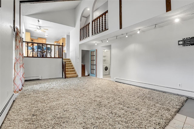 unfurnished living room with washer / clothes dryer, a baseboard heating unit, ceiling fan, stairway, and lofted ceiling