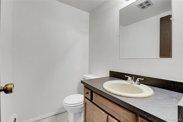 half bathroom featuring toilet, tile patterned flooring, vanity, and baseboards