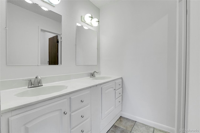 bathroom with double vanity and baseboards