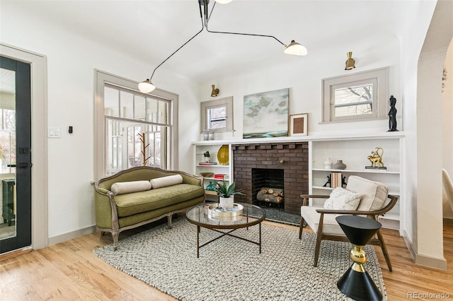 sitting room featuring a healthy amount of sunlight, light hardwood / wood-style flooring, and a brick fireplace