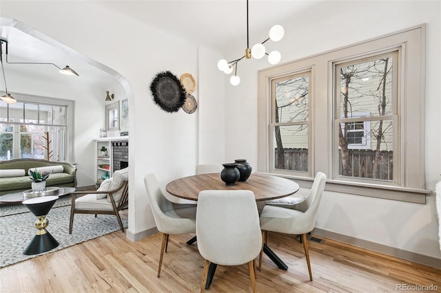 dining space featuring a brick fireplace and light hardwood / wood-style floors