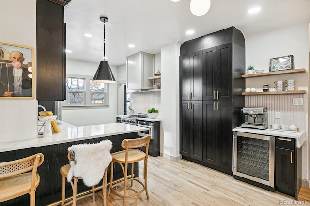 kitchen with kitchen peninsula, light hardwood / wood-style flooring, pendant lighting, tasteful backsplash, and beverage cooler