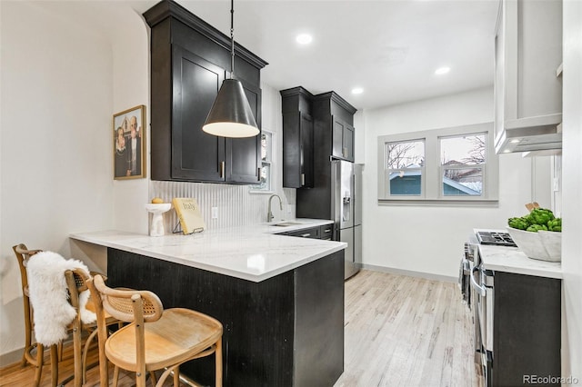 kitchen featuring light hardwood / wood-style floors, decorative backsplash, sink, kitchen peninsula, and a breakfast bar