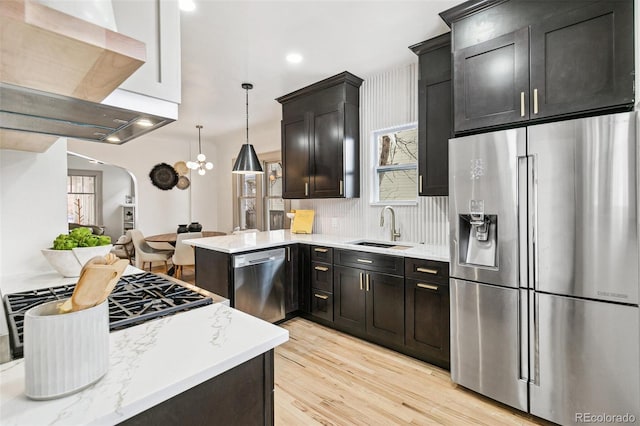 kitchen with kitchen peninsula, light hardwood / wood-style flooring, hanging light fixtures, sink, and stainless steel appliances