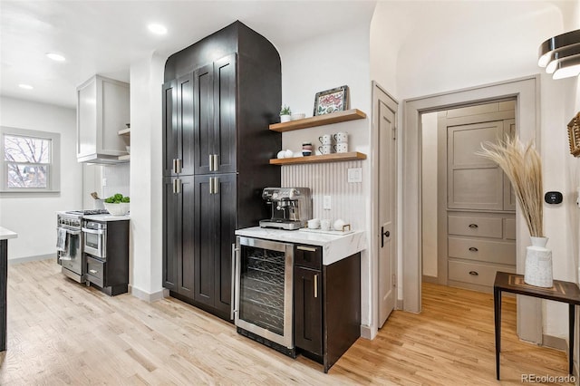 bar featuring high end range, light wood-type flooring, and wine cooler