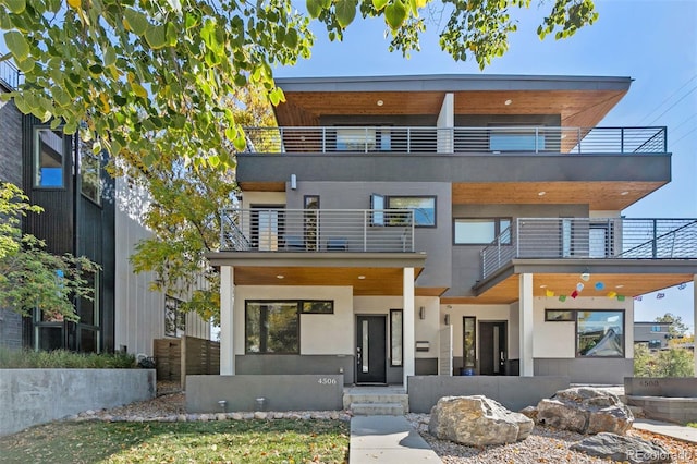 contemporary home featuring a balcony and stucco siding