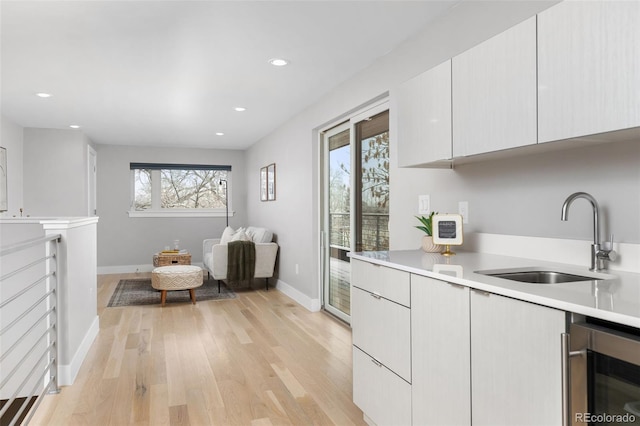 kitchen featuring beverage cooler, light countertops, a sink, and a healthy amount of sunlight