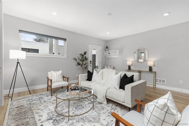 living room featuring light wood-type flooring, baseboards, visible vents, and recessed lighting