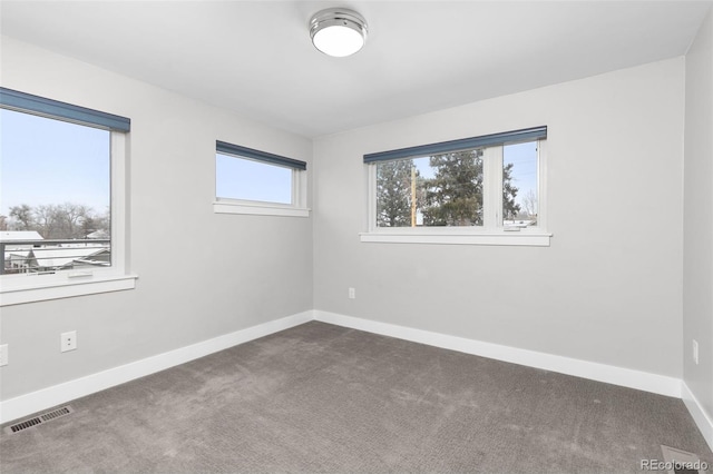 carpeted empty room featuring baseboards and visible vents