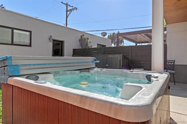 view of pool with fence and a hot tub