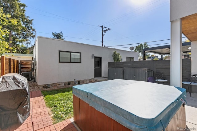 exterior space featuring fence, a grill, and a hot tub