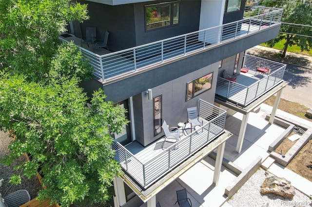 exterior space featuring a patio, a balcony, and stucco siding