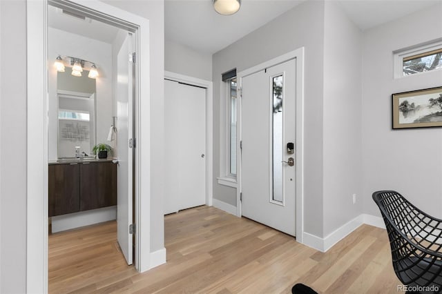 foyer featuring light wood-type flooring, visible vents, and baseboards