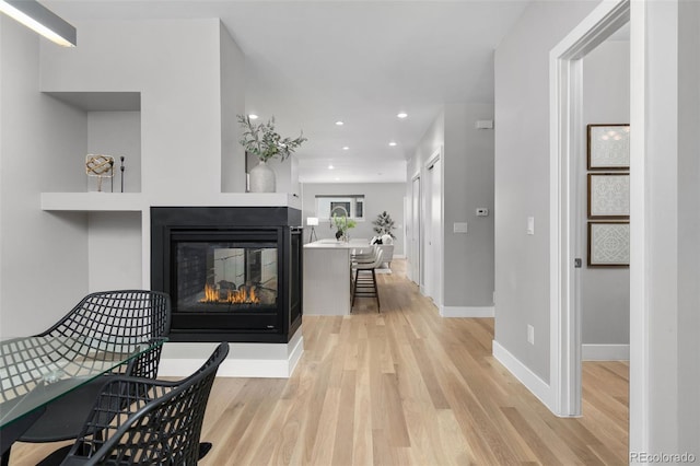 hallway with recessed lighting, light wood finished floors, and baseboards