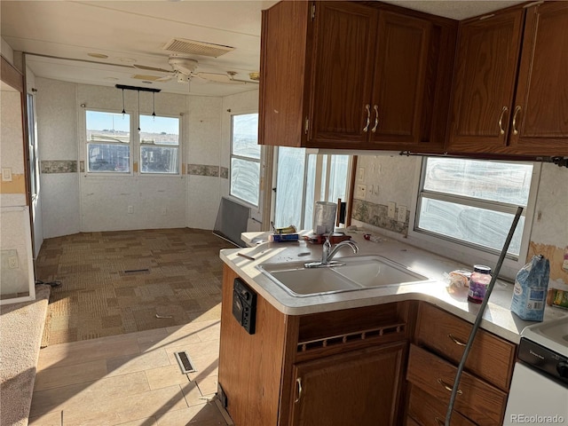 kitchen with ceiling fan, kitchen peninsula, and sink