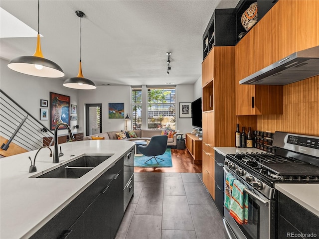 3133 Blake St Unit 3, Denver, CO 80205 - kitchen featuring stainless steel range with gas stovetop, a sink, light countertops, wall chimney exhaust hood, and dark cabinets