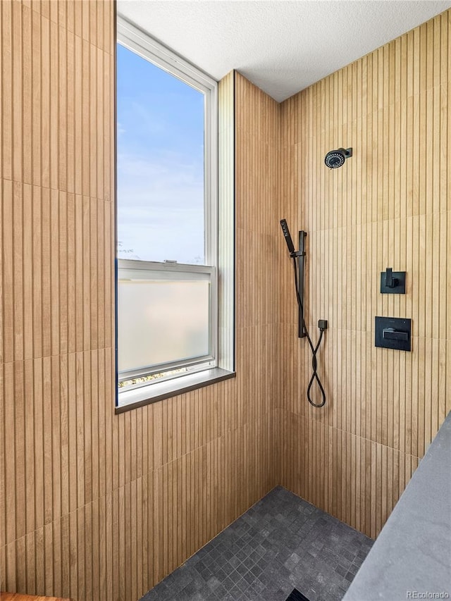 3133 Blake St Unit 3, Denver, CO 80205 - bathroom view of wooden walls, a tile shower, and a textured ceiling