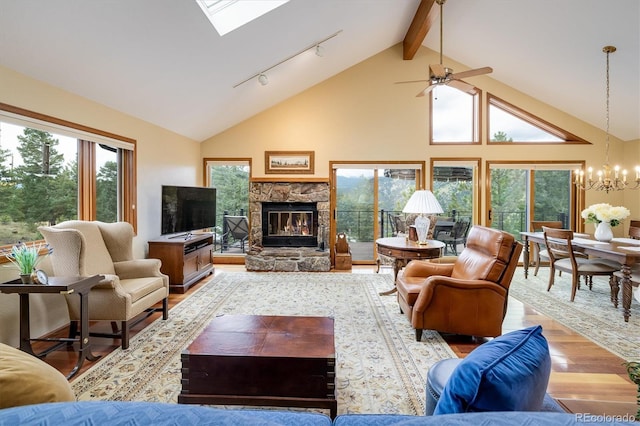 living room featuring beam ceiling, a stone fireplace, a skylight, high vaulted ceiling, and light wood-type flooring