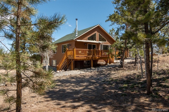 rear view of property featuring a wooden deck, stairs, and faux log siding