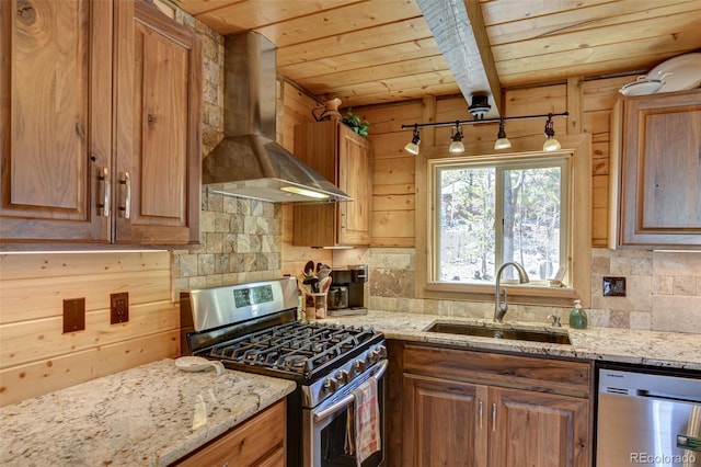 kitchen with a sink, wood ceiling, appliances with stainless steel finishes, wall chimney exhaust hood, and tasteful backsplash