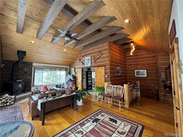 living room featuring beamed ceiling, wood ceiling, hardwood / wood-style floors, and a wood stove