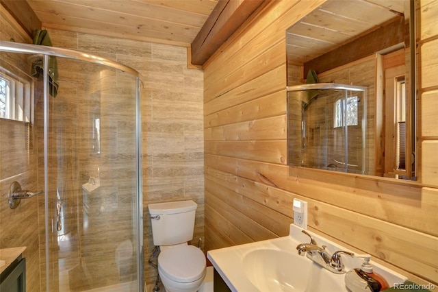 full bathroom featuring vanity, toilet, a stall shower, and wood walls