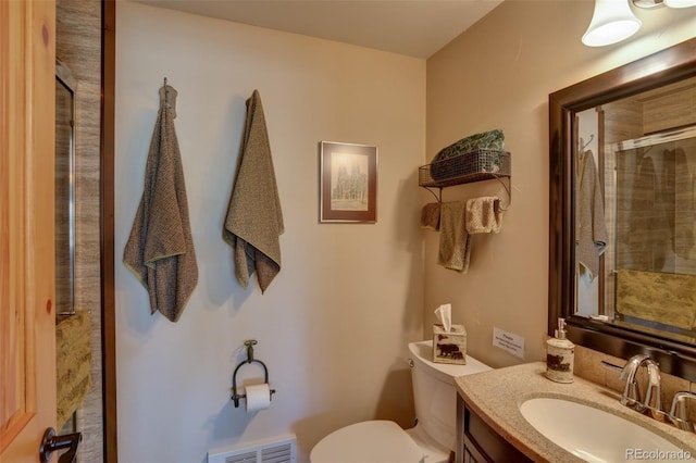 bathroom featuring a tile shower, visible vents, toilet, and vanity