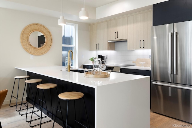 kitchen with sink, hanging light fixtures, stainless steel appliances, light hardwood / wood-style flooring, and a breakfast bar