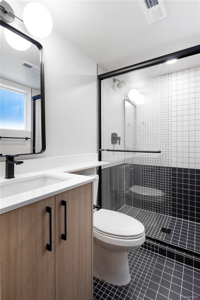 bathroom featuring tile patterned floors, vanity, toilet, and a shower with door