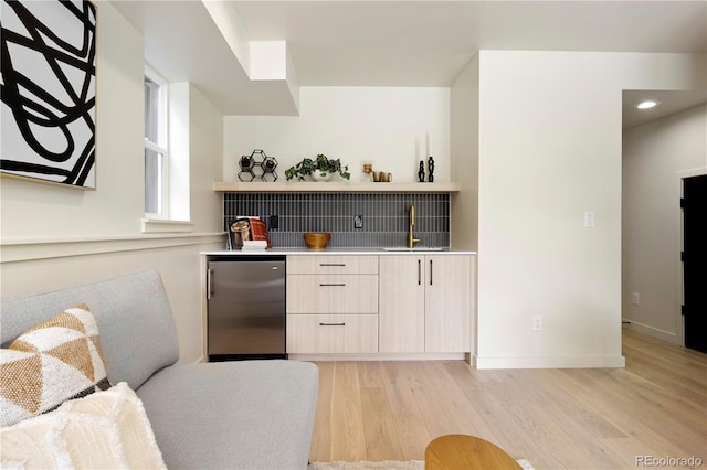 bar featuring sink, stainless steel fridge, and light hardwood / wood-style flooring