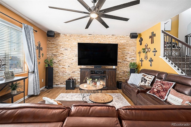 living room featuring ceiling fan, light wood-type flooring, and a fireplace