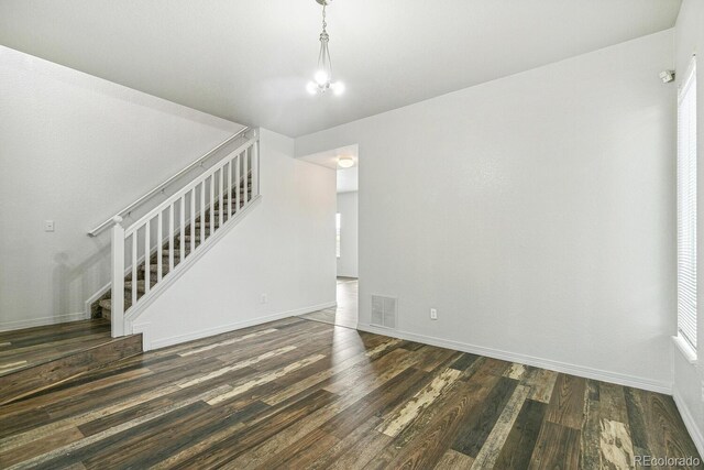 15762 Olmsted Pl, Denver, CO 80239 - unfurnished living room with stairway, dark wood-style flooring, a chandelier, and baseboards