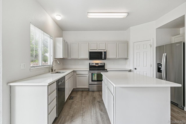 15762 Olmsted Pl, Denver, CO 80239 - kitchen with stainless steel appliances, a sink, wood finished floors, a center island, and light countertops
