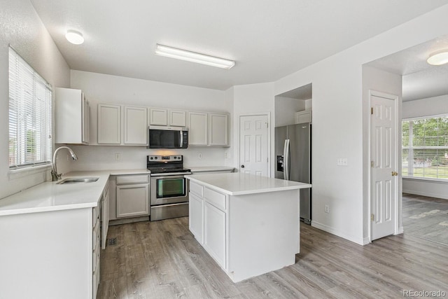 15762 Olmsted Pl, Denver, CO 80239 - kitchen featuring stainless steel appliances, a sink, light wood finished floors, a center island, and light countertops
