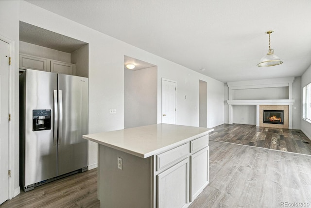 15762 Olmsted Pl, Denver, CO 80239 - kitchen with stainless steel fridge with ice dispenser, wood finished floors, a kitchen island, hanging light fixtures, and light countertops