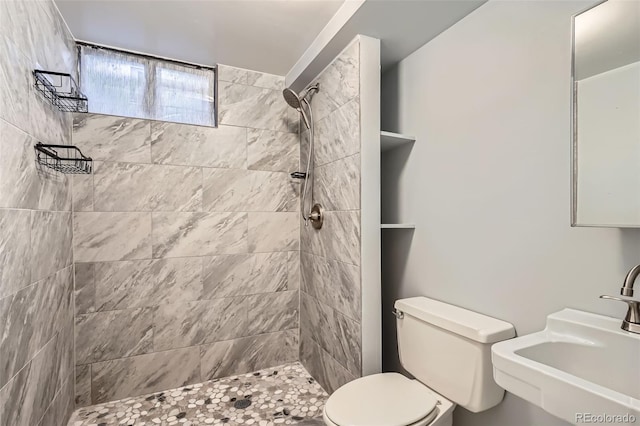 bathroom featuring toilet, sink, and a tile shower