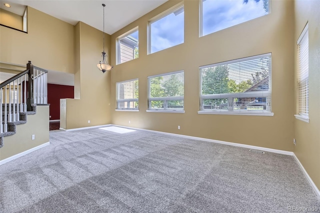 9975 Blackbird Cir, Highlands Ranch, CO 80130 - unfurnished living room featuring carpet floors, a towering ceiling, and stairs